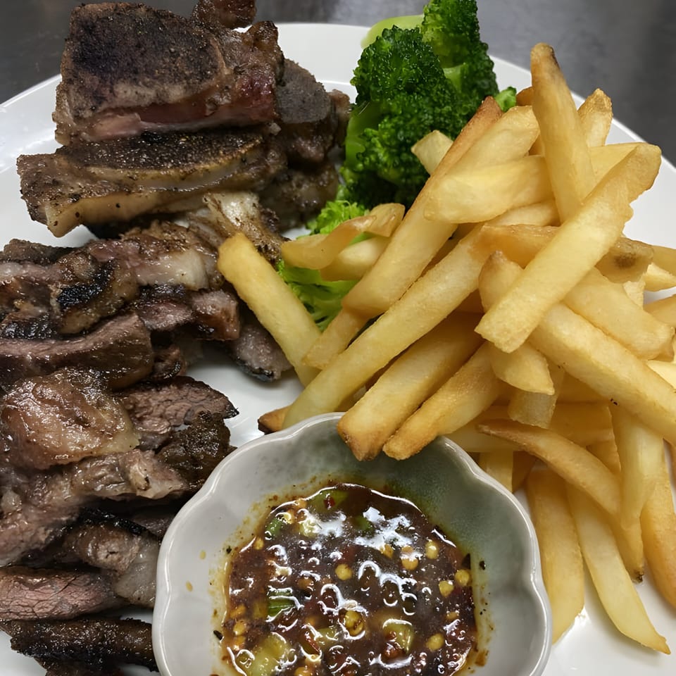 Grilled Thai beef short ribs and sliced beef with fries, broccoli, and a dipping sauce.